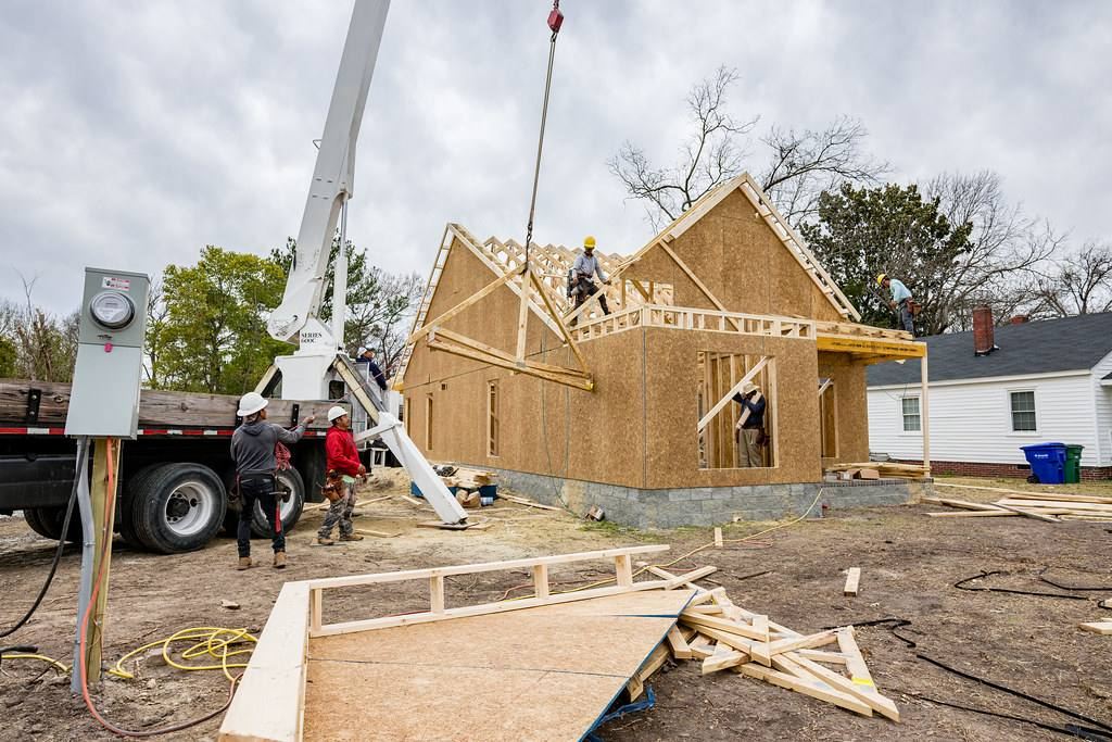Construction crew framing a wood-frame house on an active residential job site