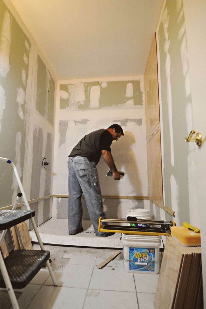A worker finishing drywall walls in a room being remodeled