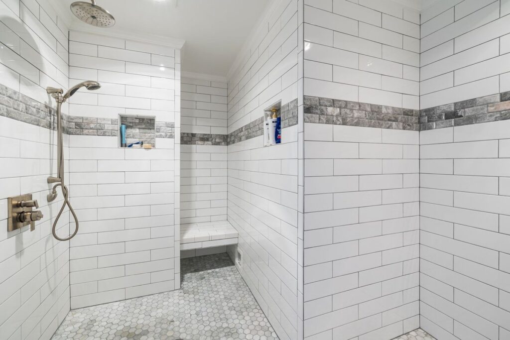 Walk-in shower with a white marble hexagon mosaic tile floor and subway-tiled walls