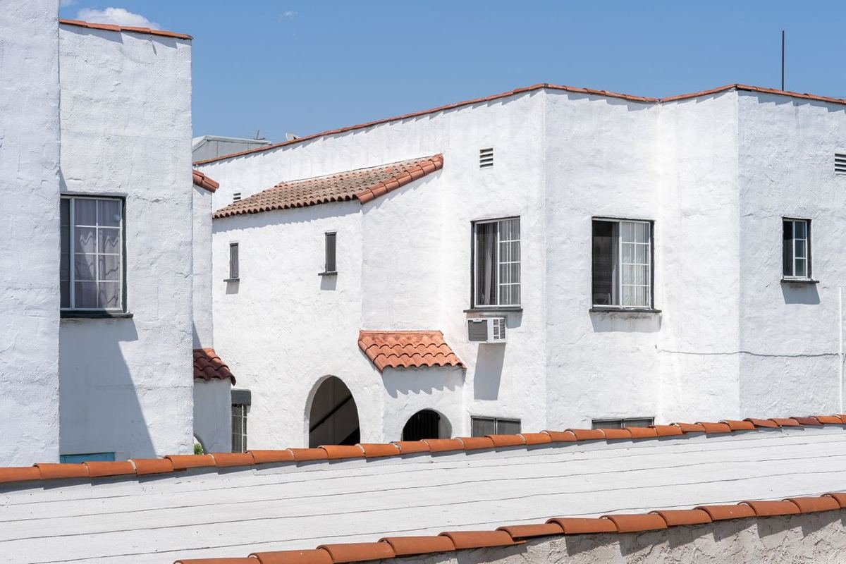 A white stucco California home with a red clay tile roof under a clear blue sky